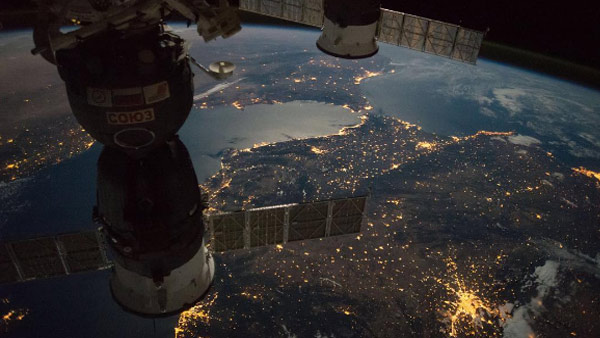 The moon and city lights illuminate the night views of Earth.

Expedition 49 crew members capture a nighttime view of the Strait of Gibraltar with a Russian Soyuz spacecraft (left) and Progress resupply spacecraft (right) in the foreground.
Image...