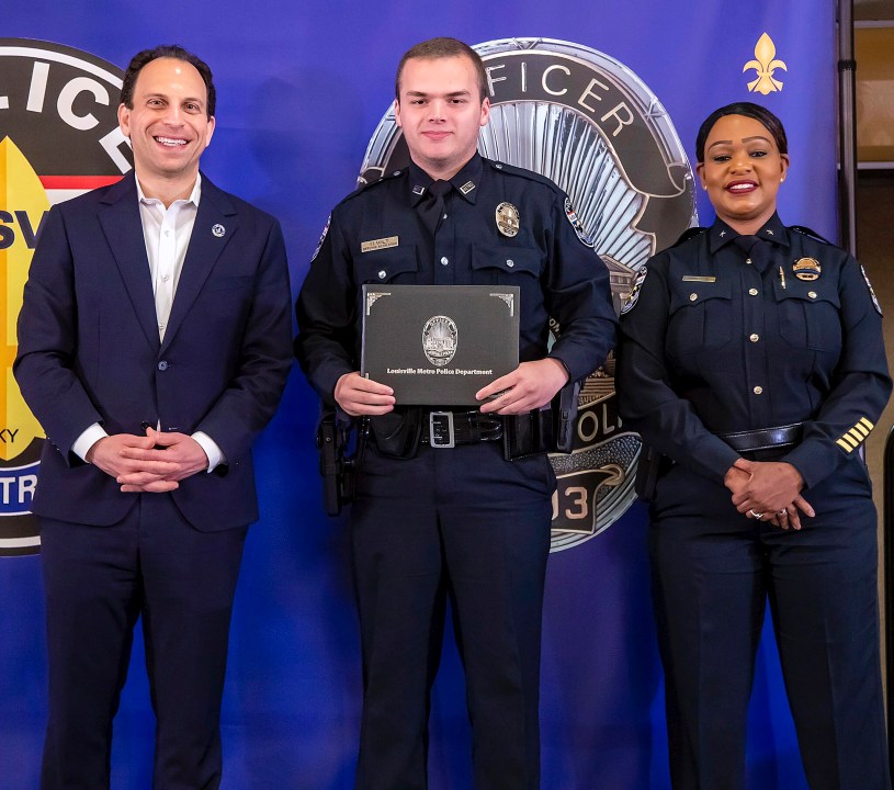 In this photo provided by the Louisville Metro Police Department, from left, Louisville Mayor Craig Greenberg, Officer Nickolas Wilt and Louisville Metro Interim Police Chief Jacquelyn Gwinn-Villaroel pose for a photo, in Louisville, Ky., March 31, 2023. Wilt was shot while responding to a call where a bank employee armed with a rifle opened fire at his workplace early Monday, April 10. (Louisville Metro Police Department via AP)