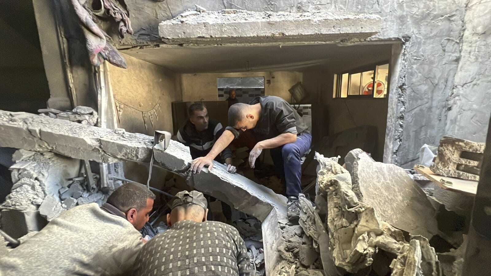 People look through the rubble of a home destroyed by an Israeli airstrike on Dec. 6, 2023, in Nuseirat refugee camp in the Gaza Strip. Four-year-old Omar Abu Kawaik was pulled alive from the rubble and brought out of Gaza then flown to the United States, where he received treatment including a prosthetic arm. (Courtesy of Maha Abu Kuwaik via AP)