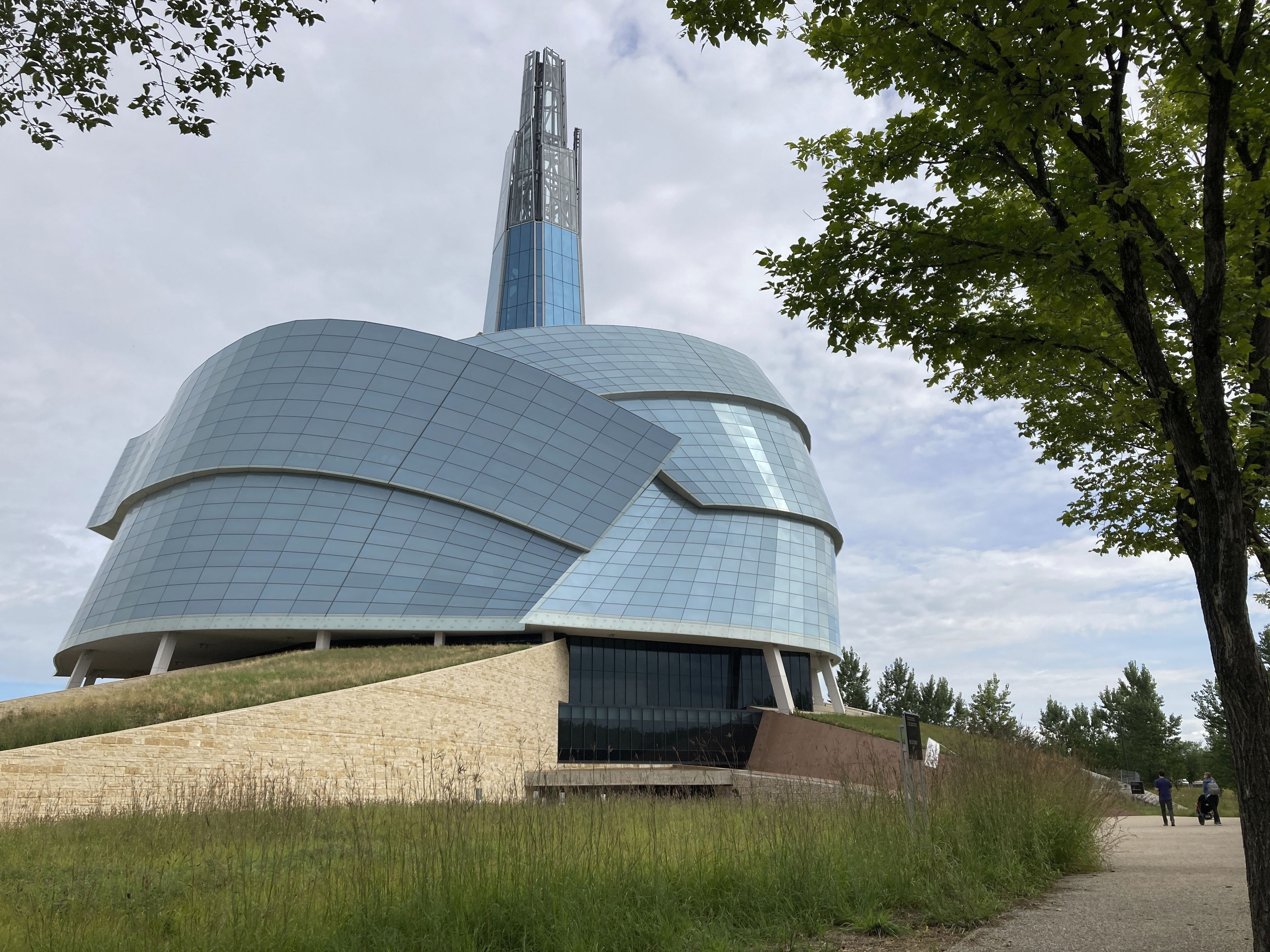 People walk by the Canadian Museum for Human Rights, created by internationally renowned architect Antoine Predock on Aug. 13, 2023, in Winnipeg, Manitoba. Predock, whose list of credits includes award-winning buildings around the world, died Saturday, March 2, 2024, at his home in Albuquerque, according to longtime friends and colleagues. He was 87. (AP Photo/Felicia Fonseca)