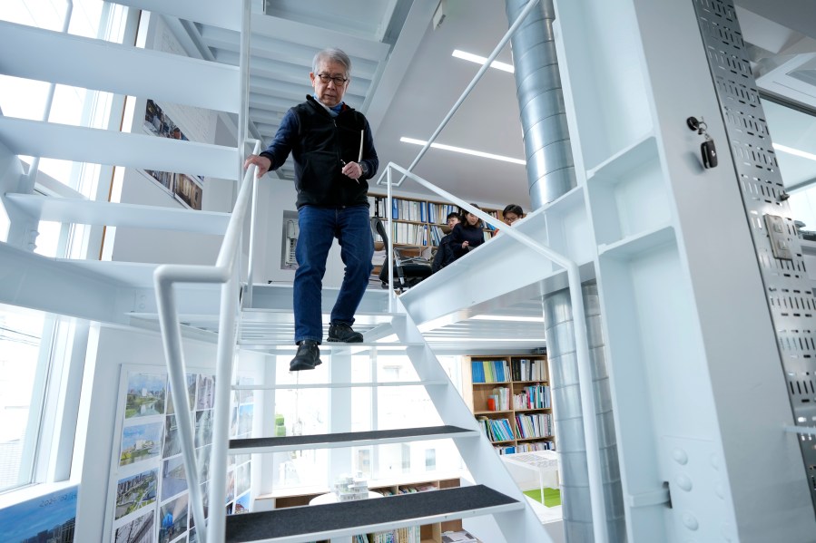 Japan's Riken Yamamoto, laureate of Pritzker Architecture Prize, walks down the stairs at his office Wednesday, March 6, 2024, in Yokohama near Tokyo. The Pritzker Architecture Prize has been awarded to Japan’s Riken Yamamoto, who earns the field’s highest honor for what organizers called a long career focused on "multiplying opportunities for people to meet spontaneously, through precise, rational design strategies." (AP Photo/Eugene Hoshiko)